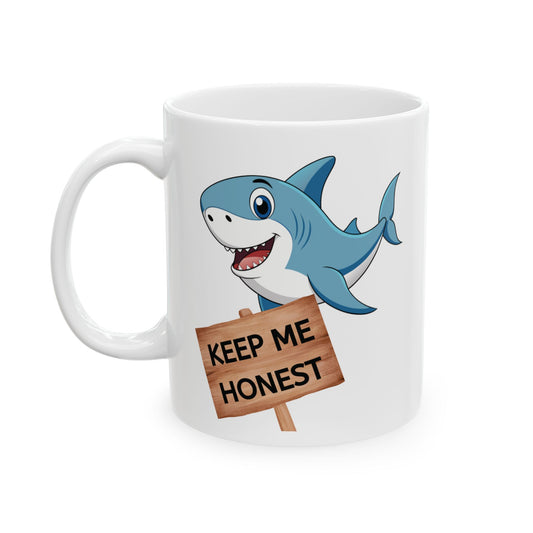 White ceramic funny coffee mug with a blue and white shark smiling with mouth open, teeth and tongue showing, and a sign with the words "Keep me honest"