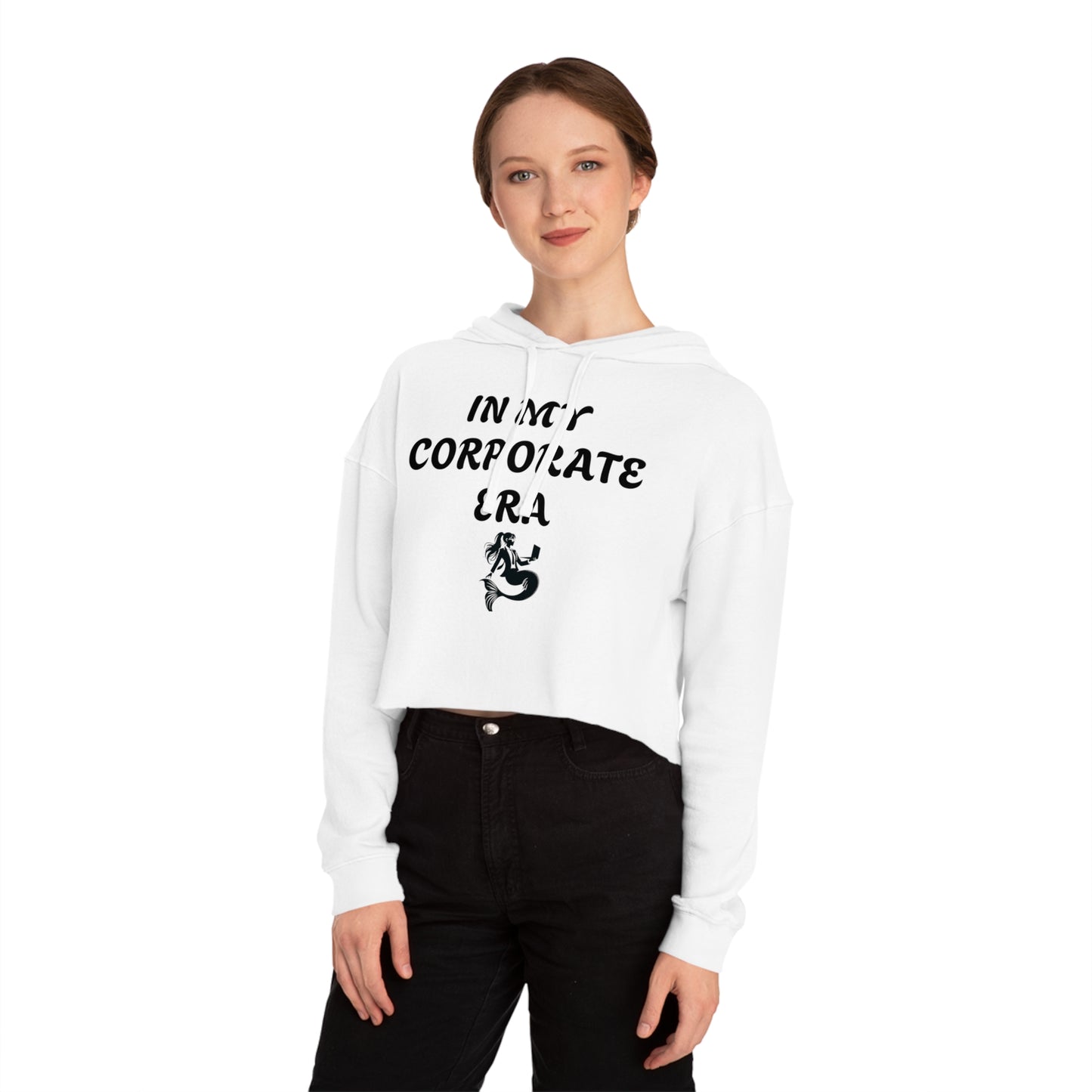 White cropped hoodie with "In my corporate Era" written in black with the corporate mermaid logo which is a mermaid wearing a suit and gasses, hair in a pony tail and holding an open laptop. Worn by a female model with brown hair and wearing black jeans