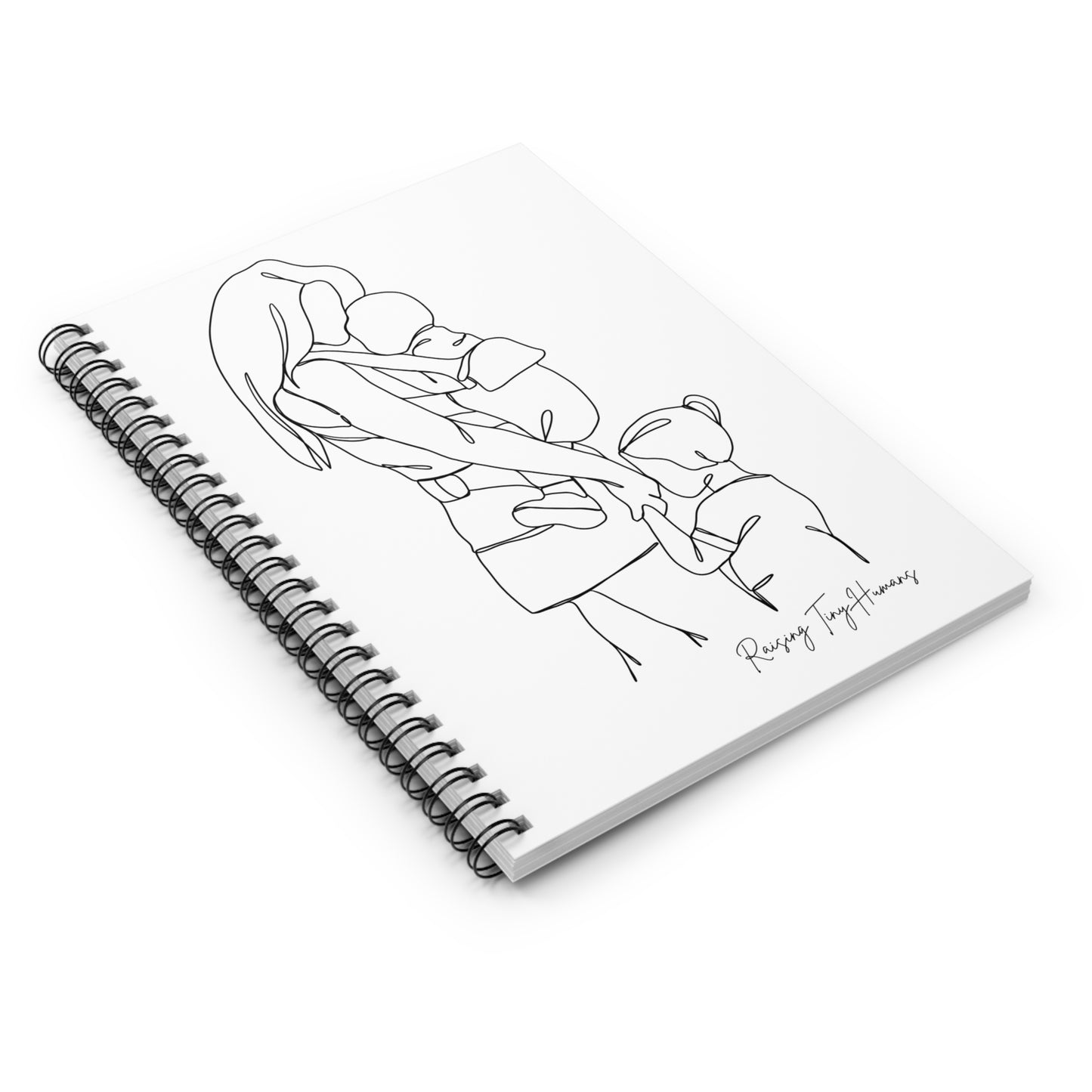 Lying spiral bound notebook, with a cover featuring a simple line drawing of a mother holding a baby in a wearing carrier and holding the hand of a toddler, with the caption "Raising Tiny Humans" featured in handwriting in the bottom right corner of the cover